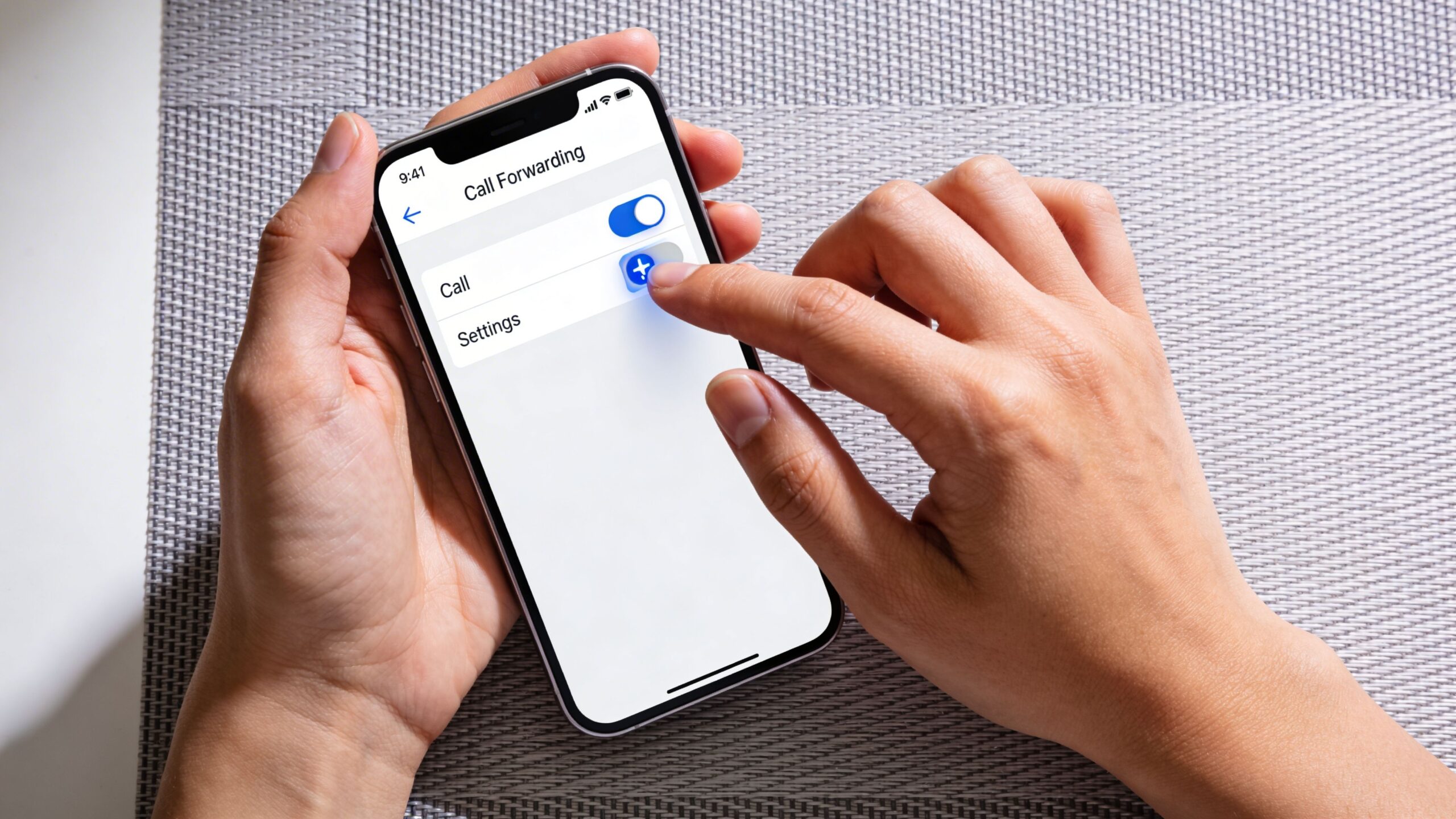 A person holding a smartphone and adjusting the call forwarding settings on the device screen.